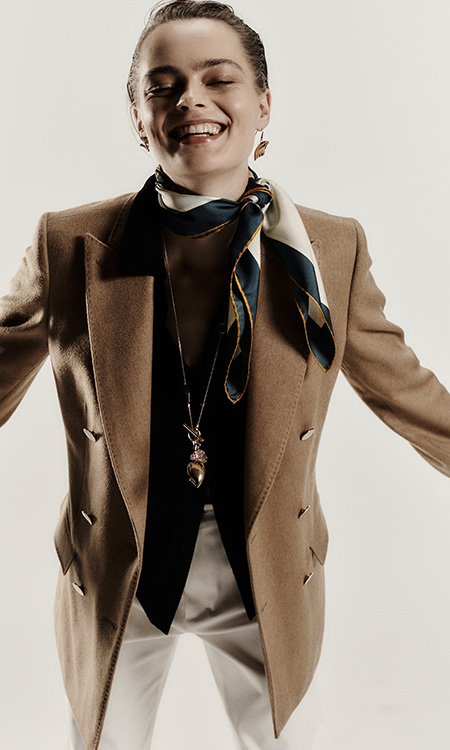 Model wears Max Mara Sartoriale double-breasted blazer in broadcloth camel drap with foulard and light trousers.